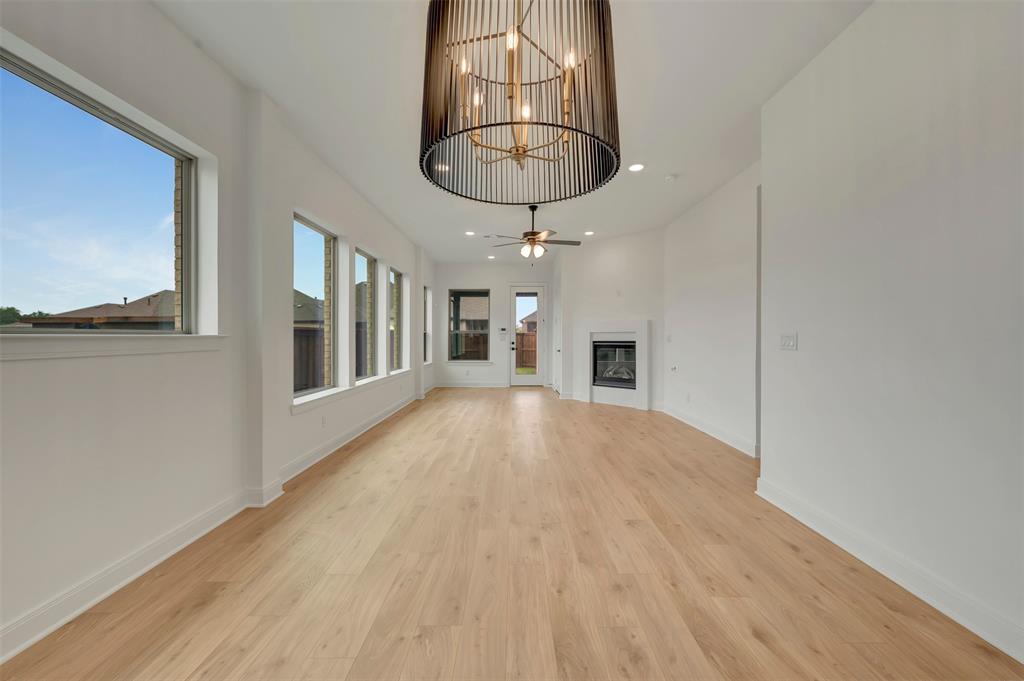 1856 Lightner Road Van Alstyne, TX 75495 - Photo 18 of 33 Spacious interior featuring light wood-finish flooring, a contemporary chandelier, multiple windows for ample light, a modern fireplace, and recessed ceiling lights