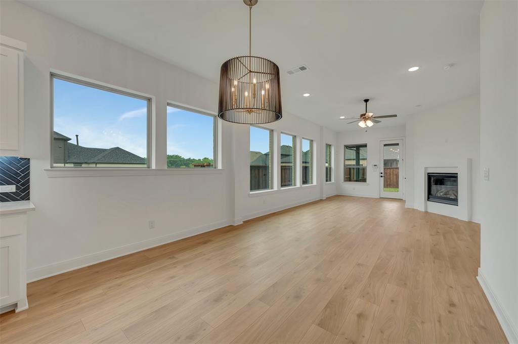 1856 Lightner Road Van Alstyne, TX 75495 - Photo 20 of 33 Open-concept living area with abundant natural light, wood-finish flooring, a modern fireplace, and a contemporary light fixture