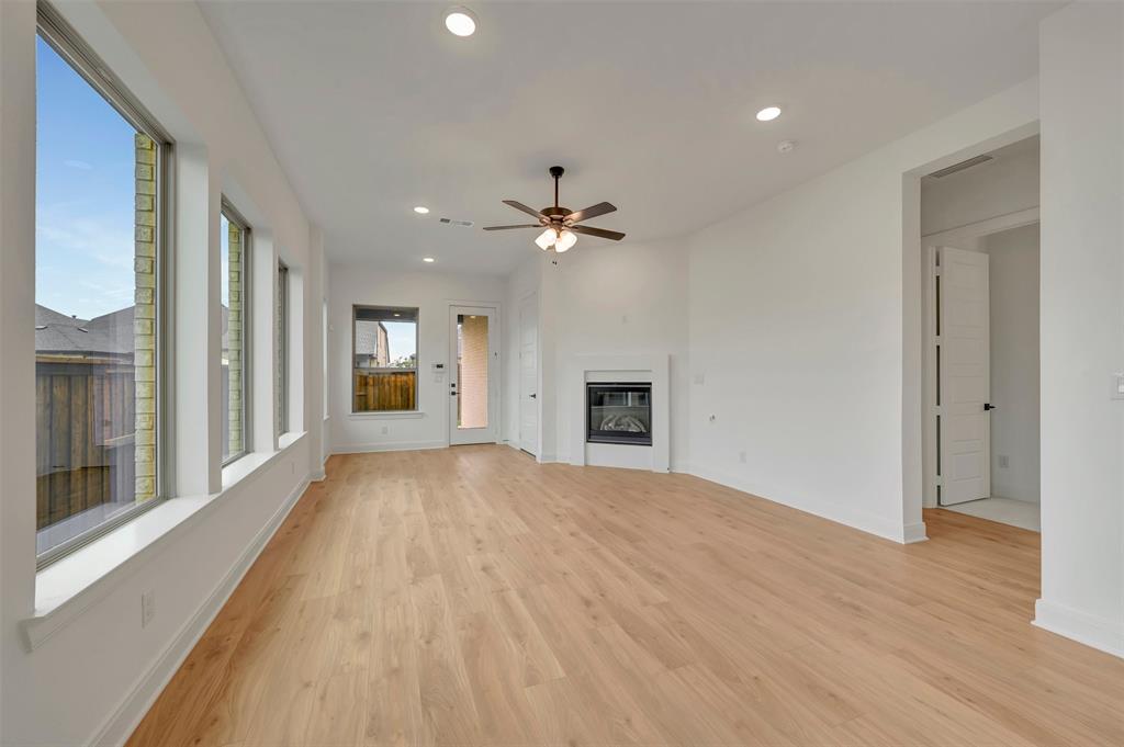 1856 Lightner Road Van Alstyne, TX 75495 - Photo 22 of 33 Spacious room featuring wood-finish flooring, multiple large windows, a ceiling fan, recessed lighting, and a built-in fireplace