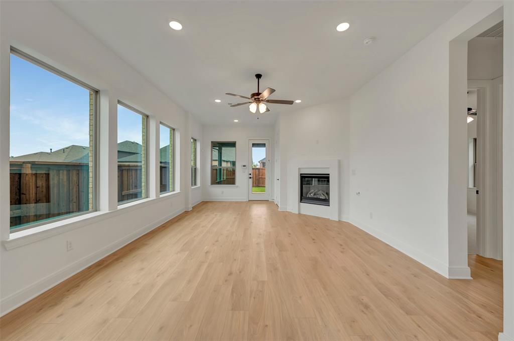 1856 Lightner Road Van Alstyne, TX 75495 - Photo 23 of 33 Spacious living area featuring expansive windows, wood-finish flooring, recessed lighting, and a modern fireplace with a white surround