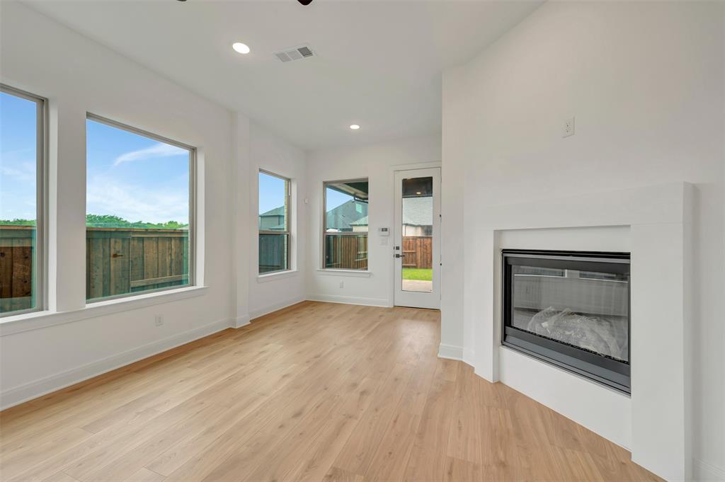1856 Lightner Road Van Alstyne, TX 75495 - Photo 26 of 33 Living area with light wood-finish flooring, a contemporary fireplace, recessed lighting, and multiple large windows