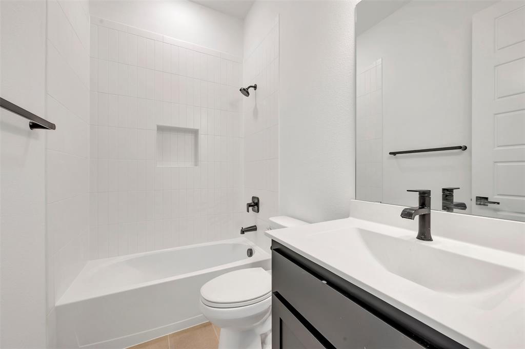 1856 Lightner Road Van Alstyne, TX 75495 - Photo 29 of 33 Contemporary bathroom featuring a white tile shower surround with a recessed niche, a white bathtub, and a modern vanity with a dark cabinet base and integrated sink