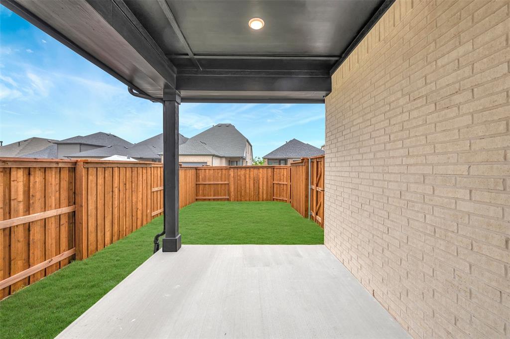 1856 Lightner Road Van Alstyne, TX 75495 - Photo 3 of 33 Covered patio with a concrete surface, light-colored brick exterior, and a fenced backyard featuring a manicured lawn