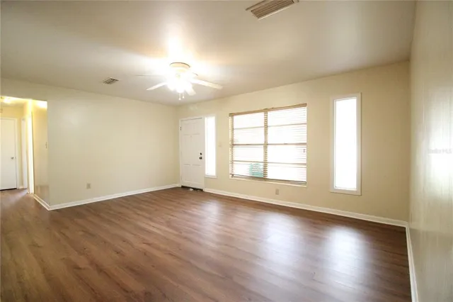 an empty room with wooden floor and windows