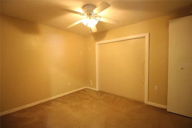 an empty room with a ceiling fan and a window