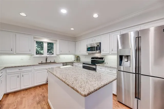 a kitchen with sink a refrigerator and white cabinets