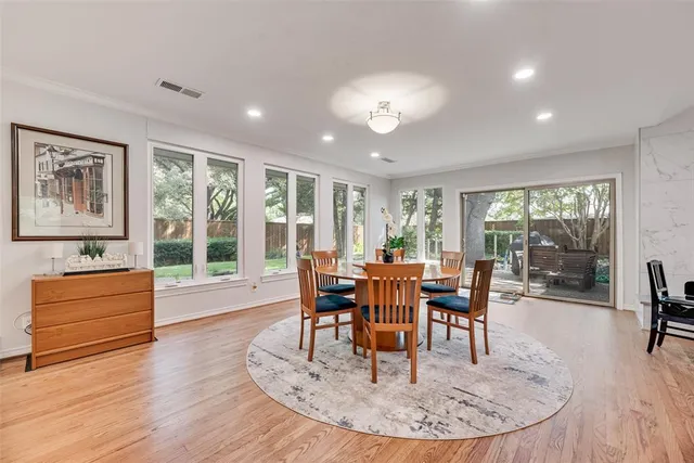 a dining room with wooden floor a chandelier a wooden table and chairs