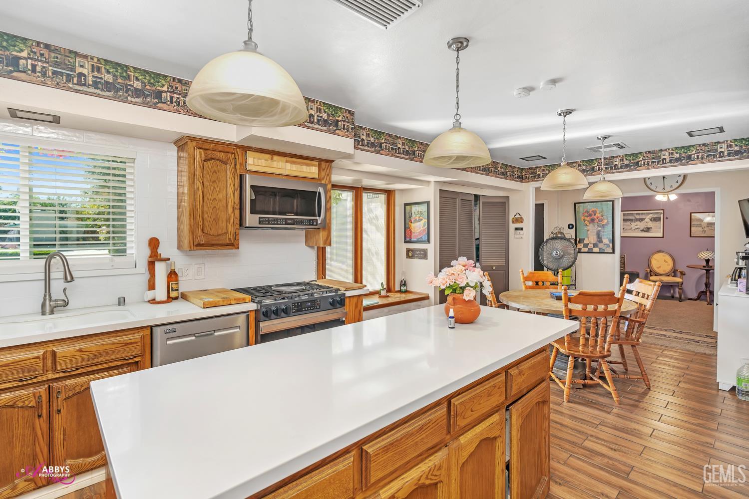 Undisclosed Address Bakersfield, CA 93306 - Photo 14 of 56 a kitchen with stainless steel appliances a stove a sink a dining table and chairs with wooden floor