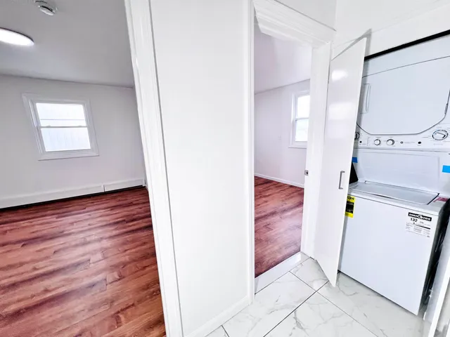 a view of a hallway with wooden floor and a bathroom