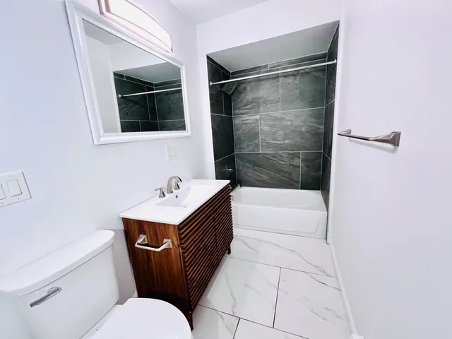 a bathroom with a granite countertop sink a mirror and a toilet