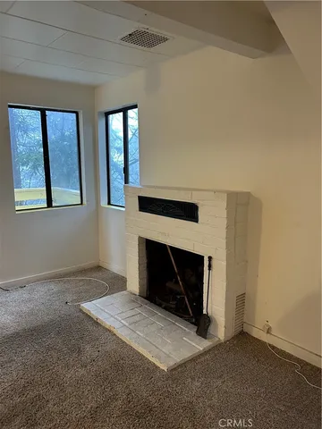 an empty room with windows and fireplace
