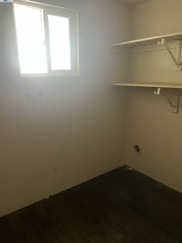 a view of kitchen and empty room with wooden floor