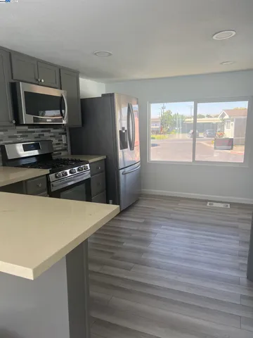 a kitchen with a refrigerator stove and wooden floor