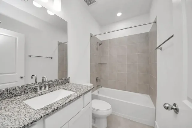 a bathroom with a granite countertop sink a toilet and shower