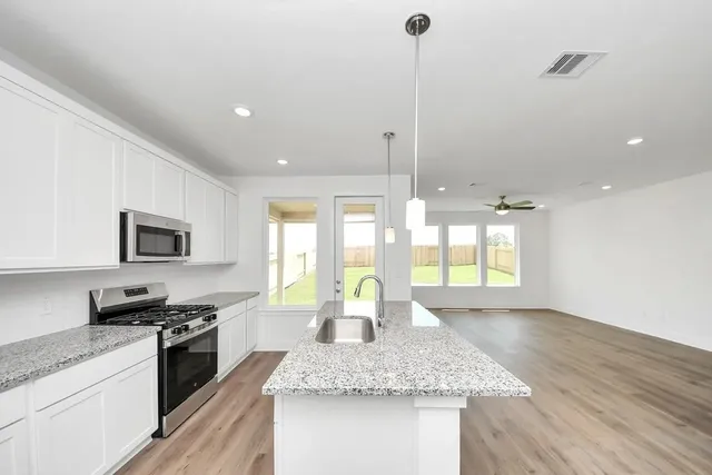 a kitchen with stainless steel appliances granite countertop a sink a stove and a wooden floors
