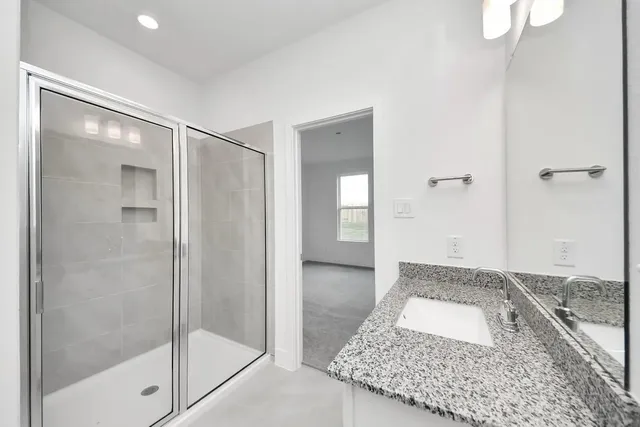 a bathroom with a granite countertop sink a mirror and a shower