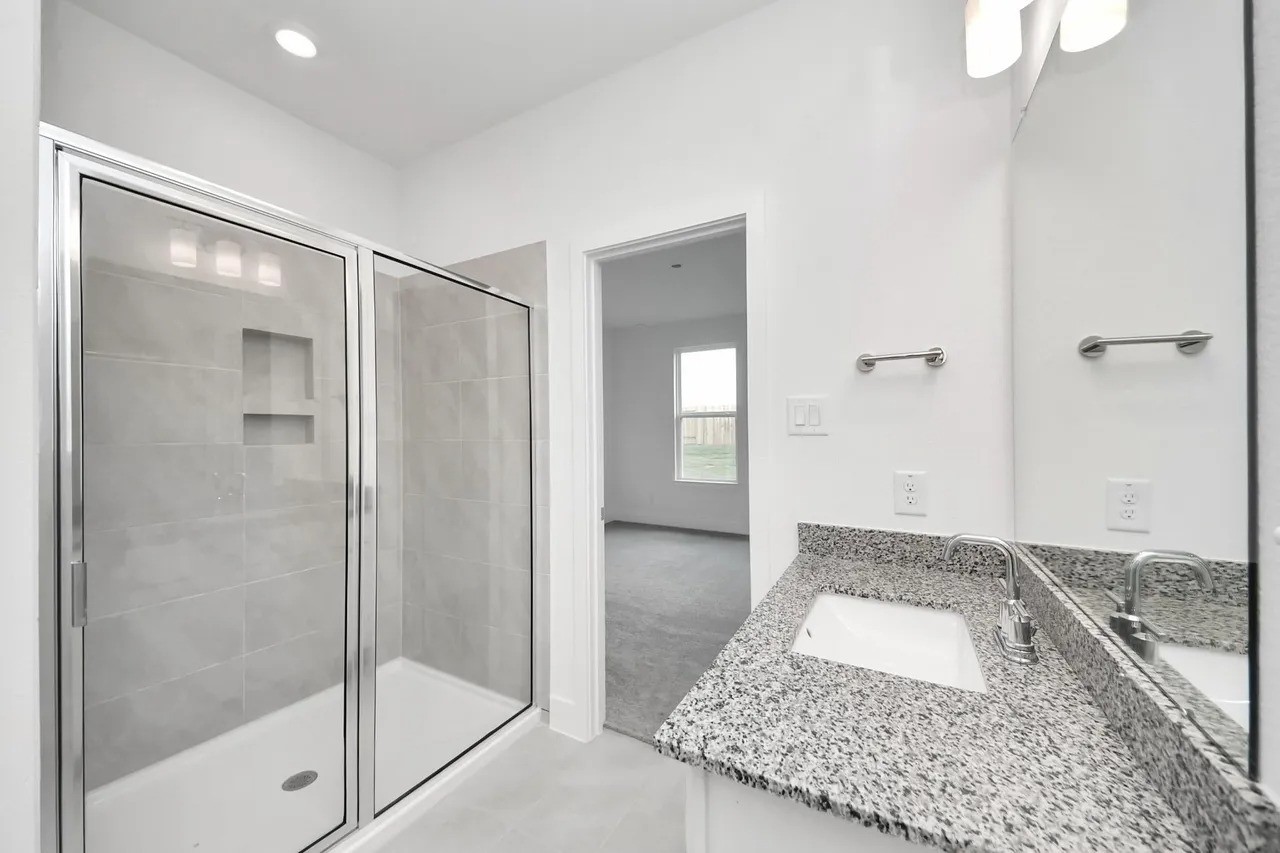 14439 Trumpet Lane Splendora, TX 77372 - Photo 9 of 15 a bathroom with a granite countertop sink a mirror and a shower