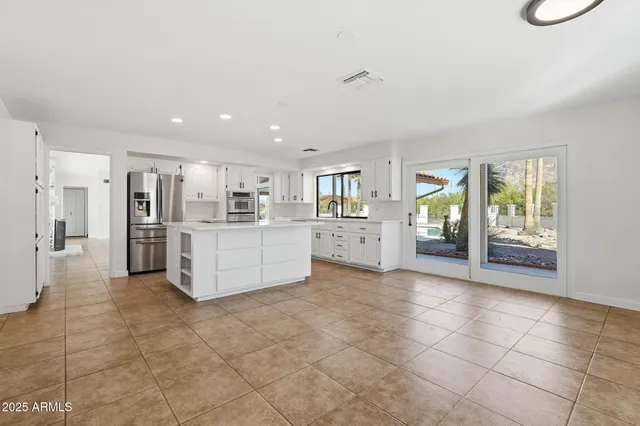 a large white kitchen with a stove a refrigerator and a sink
