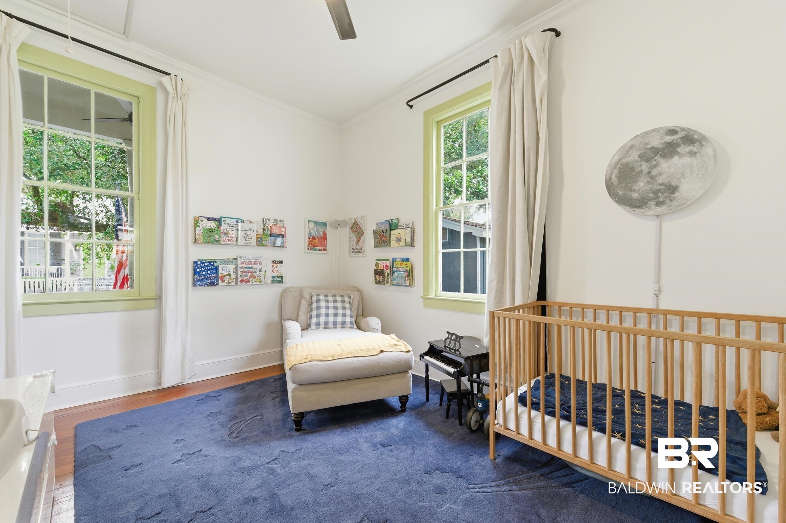 350 Charles Street Mobile, AL 36604 - Photo 25 of 52 Bright room featuring two large windows with light green trim and white curtains, a ceiling fan, and wood-finish flooring