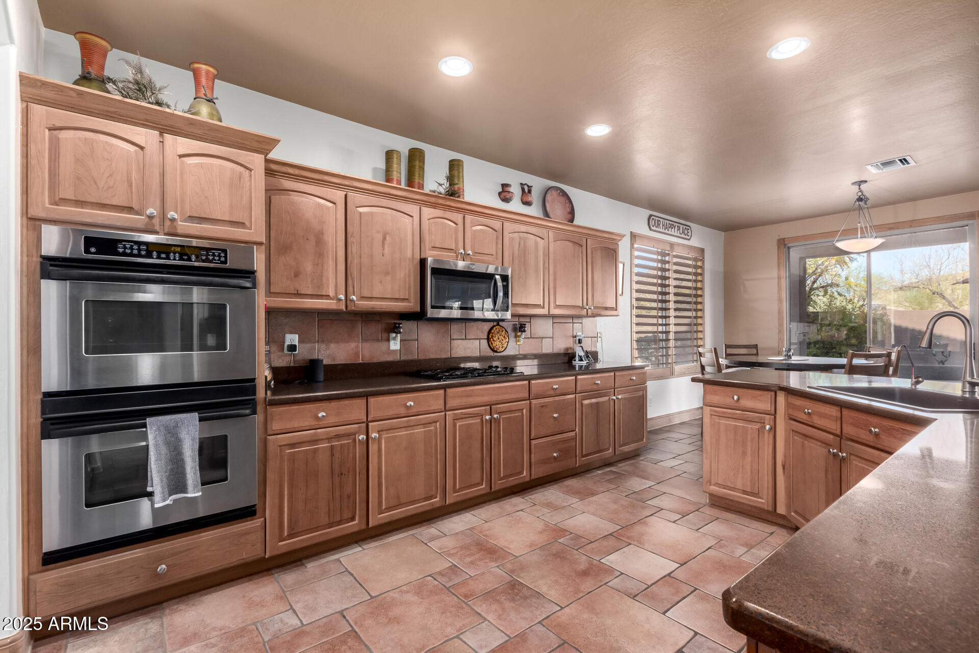 5902 West Gambit Trail Phoenix, AZ 85083 - Photo 5 of 62 a large kitchen with stainless steel appliances granite countertop a stove top oven a sink dishwasher a dining table and chairs with wooden cabinets