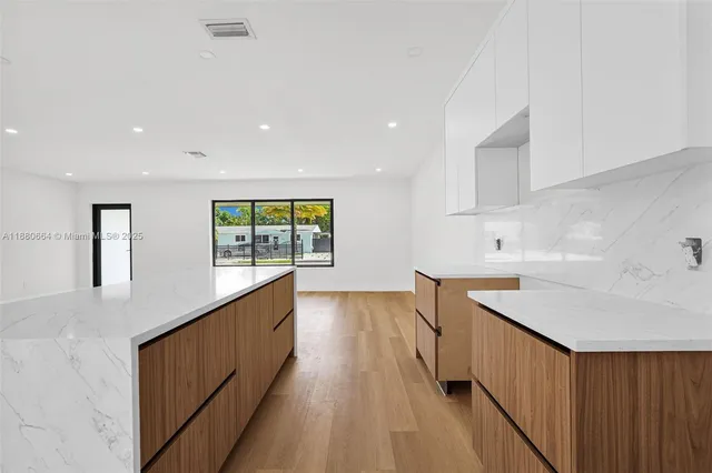 a kitchen with kitchen island a sink wooden floor and a large window
