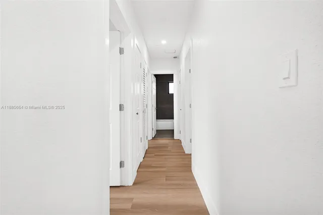 a view of a hallway with wooden floor and a bathroom