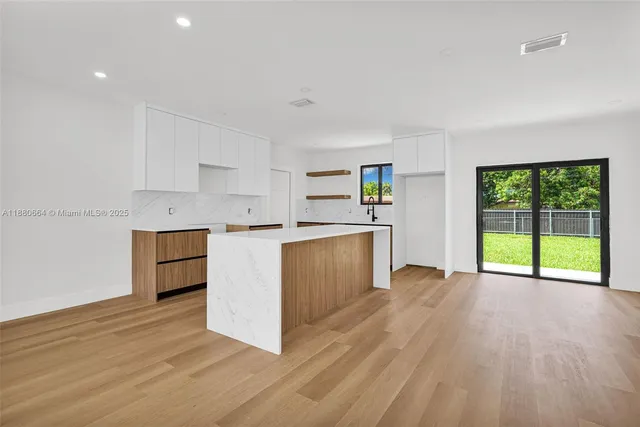 a kitchen with a white cabinets and wooden floor