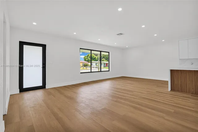 an empty room with wooden floor and a window