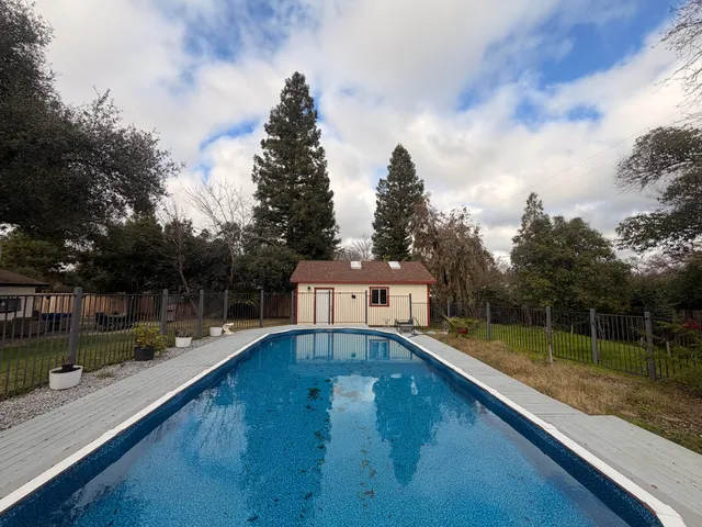 a view of backyard with large tree and wooden fence
