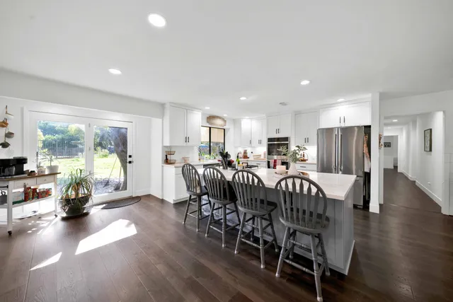 a kitchen with a dining table chairs and white cabinets