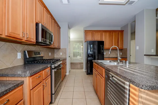 a kitchen with stainless steel appliances granite countertop a sink stove and refrigerator