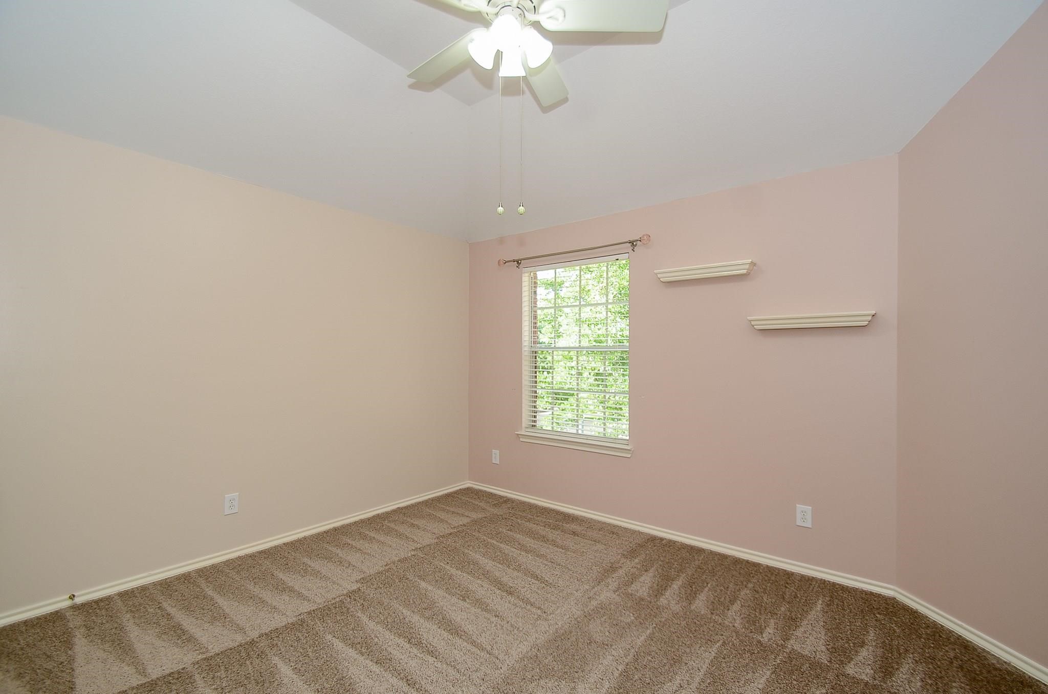 23719 Tustin Ranch Court Katy, TX 77494 - Photo 27 of 31 an empty room with a chandelier fan and windows