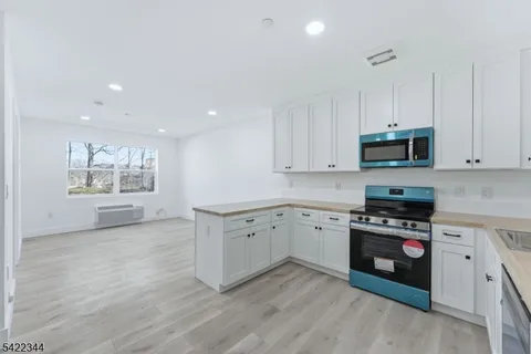 a kitchen with granite countertop white cabinets and black stainless steel appliances
