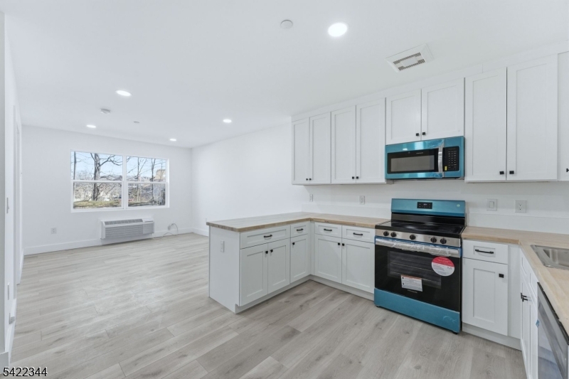 a kitchen with granite countertop white cabinets and black stainless steel appliances