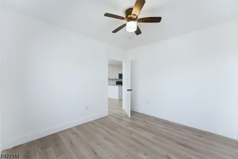 an empty room with wooden floor and a ceiling fan
