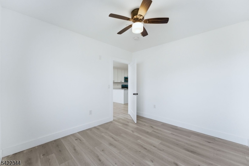 95 Shepherd Lane, Unit B302 Totowa, NJ 07512 - Photo 11 of 24 an empty room with wooden floor and a ceiling fan