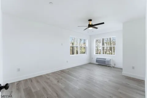 an empty room with wooden floor ceiling fan and windows