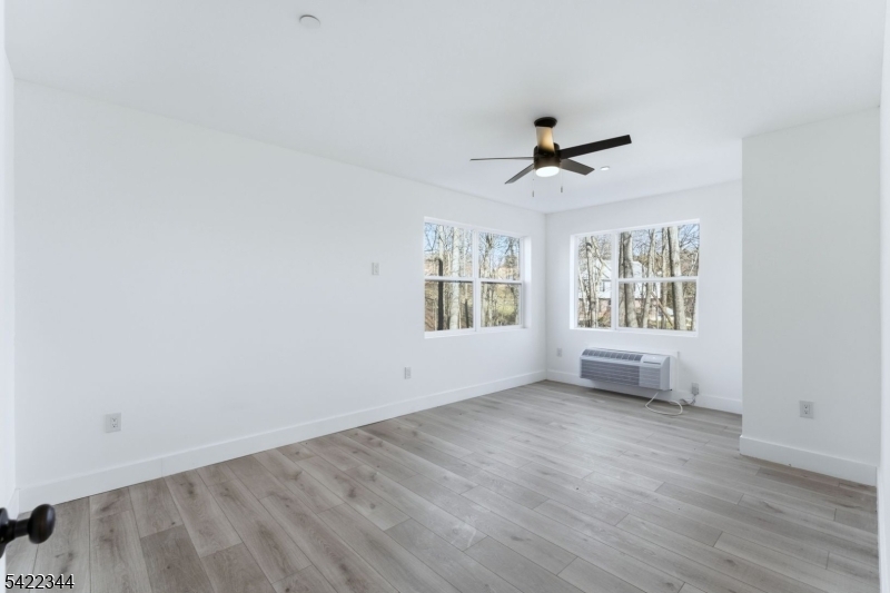 95 Shepherd Lane, Unit B302 Totowa, NJ 07512 - Photo 14 of 24 an empty room with wooden floor ceiling fan and windows