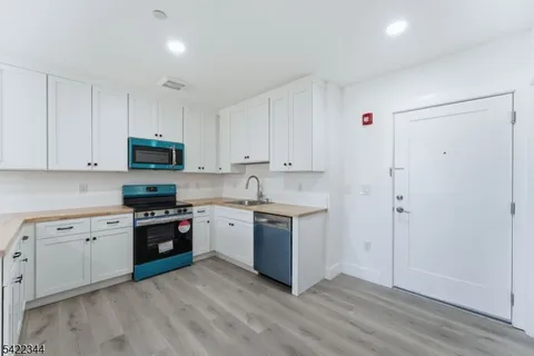 a kitchen with stainless steel appliances granite countertop a stove top oven a sink and dishwasher with white cabinets