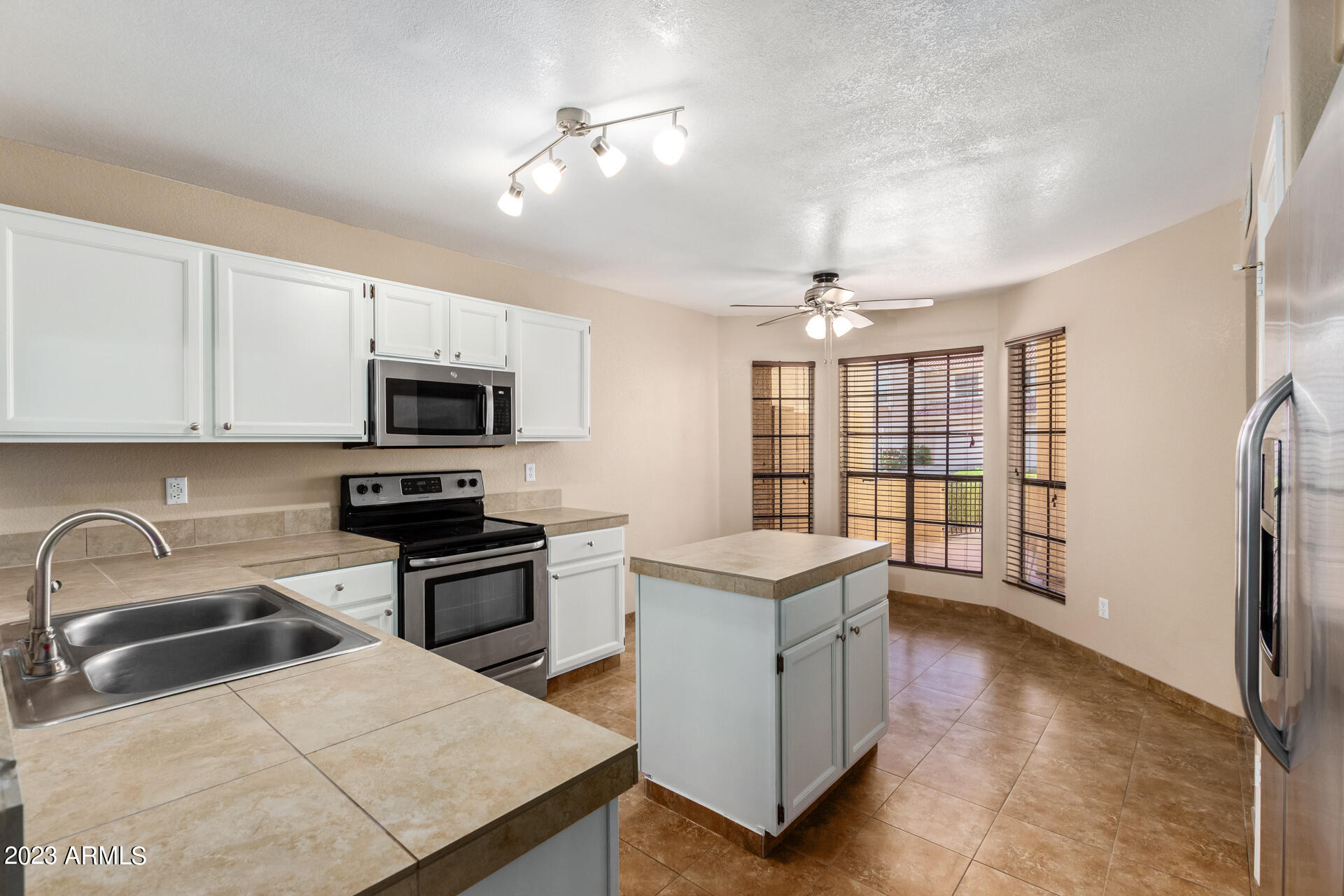 4266 East Agave Road Phoenix, AZ 85044 - Photo 10 of 54 a kitchen with stainless steel appliances kitchen island granite countertop a refrigerator a sink a stove and white cabinets