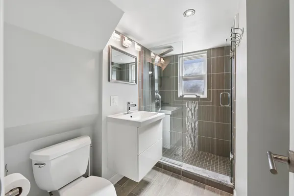 a bathroom with a shower sink mirror and toilet