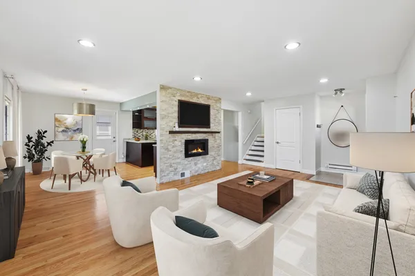 a living room with furniture a fireplace a flat screen tv and kitchen view