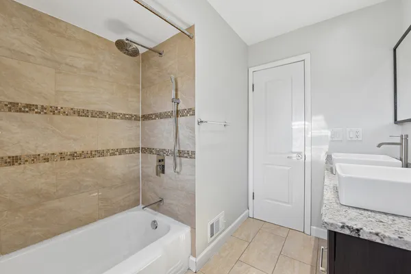 a bathroom with a granite countertop sink a mirror and a bathtub