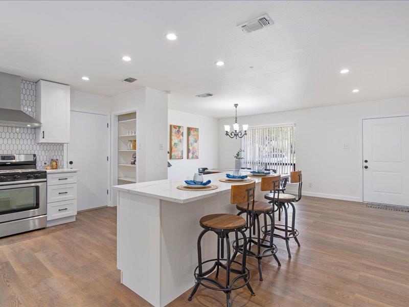 1312 Hyman Lane Austin, TX 78742 - Photo 7 of 36 The kitchen features a white tile backsplash, stainless steel appliances, and a central island with a white countertop