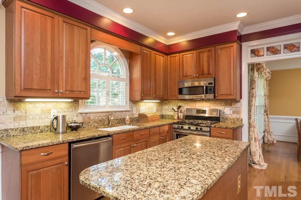 5215 Coffee Tree Drive Raleigh, NC 27613 - Photo 4 of 25 The remodeled kitchen features gorgeous granite countertops, cherry soft-close cabinets and stone-tile backsplash