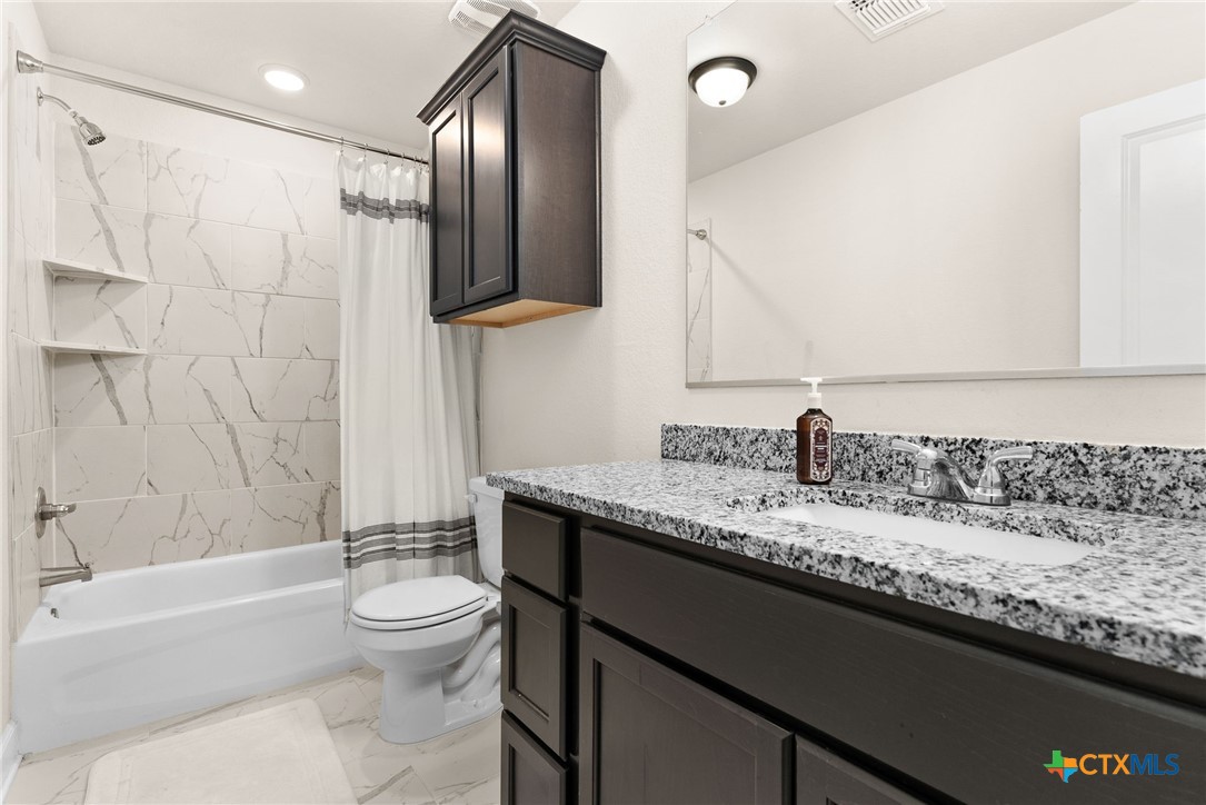 5712 Redfish Court Belton, TX 76513 - Photo 27 of 37 a bathroom with a granite countertop sink a toilet and a bathtub