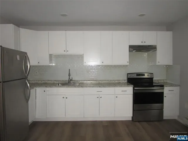 a kitchen with granite countertop white cabinets and stainless steel appliances