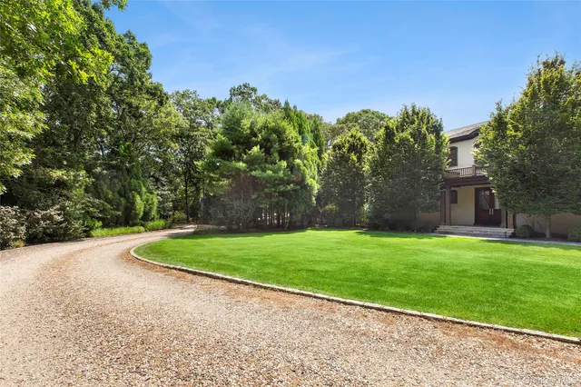 a front view of a house with garden and trees