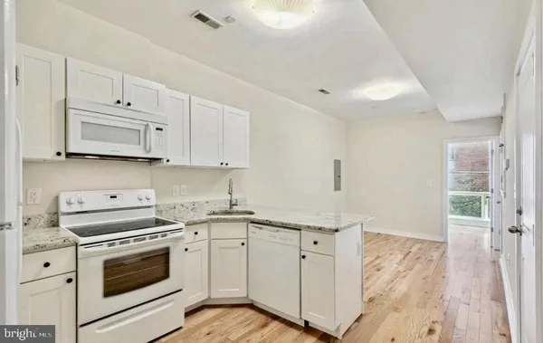 a kitchen with granite countertop white cabinets and white appliances