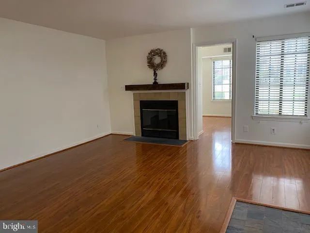 an empty room with wooden floor fireplace and windows